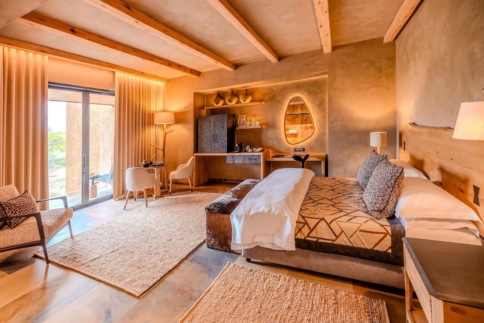 A warmly lit lodge suite with timber beams, plaster walls and doors onto a private deck